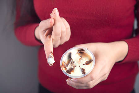 happy woman eat chocolate cream on grey backgroundの写真素材