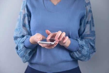 woman hand holding smart phone on grey background