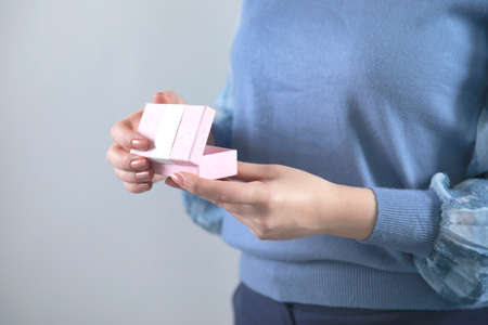 woman hand holding pink gift box on grey background
