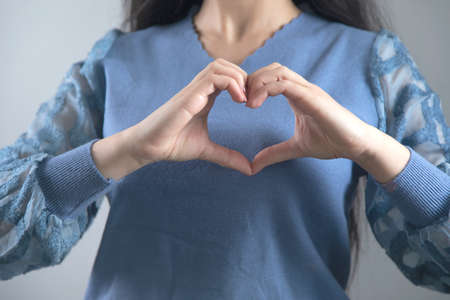 woman hand heart sign on grey background