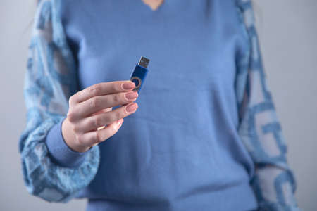 woman hand holding flash drive on grey background