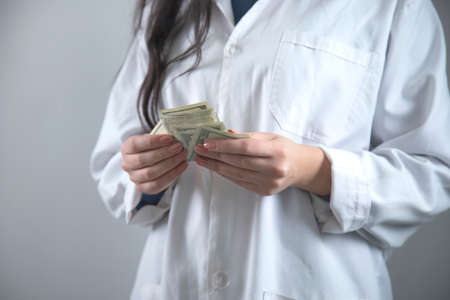 woman doctor hand money on grey backgroundの写真素材