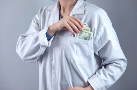 doctor hand money in pocket on grey background