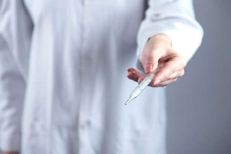 doctor face mask hand thermometer on grey background