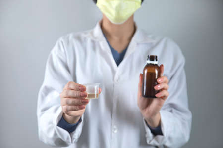 woman doctor hand syrup on grey background