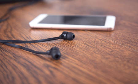 Earphone and smart phone on the table background