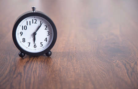 clock on the wooden table backgroundの写真素材