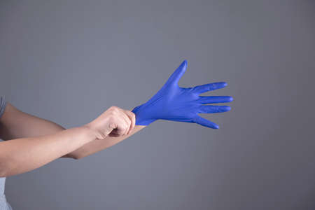 woman hand blue glove on grey backgroundの写真素材
