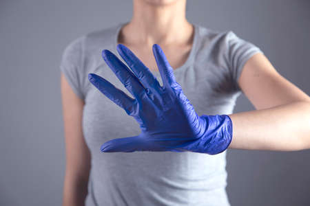 woman hand blue glove and stop sign on grey backgroundの写真素材