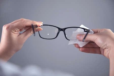 woman cleaning glasses on grey backgroundの写真素材