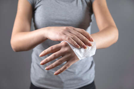 woman clean hand in napkin on grey background
