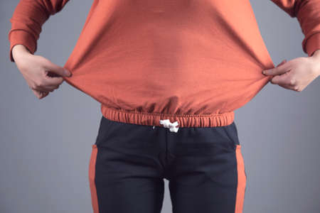 gaining weight woman on grey wall background