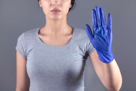 woman hand blue glove and stop sign on grey backgroundの写真素材
