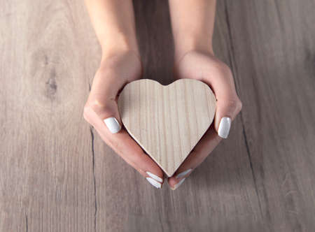 woman hand wooden heart on tableの写真素材