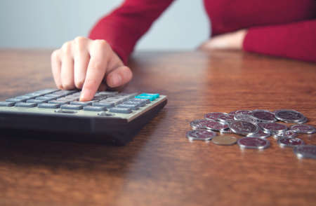 woman hand calculator and coins on tableの写真素材