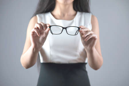 young business young woman hand glasses on grey backgroundの写真素材