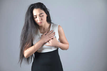 young woman hand in ache heart on grey backgroundの写真素材