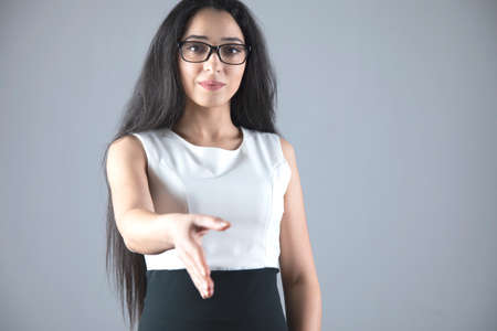 young business woman greet by hand on grey backgroundの写真素材