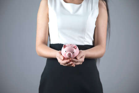 business woman hand piggy bank on grey backgroundの写真素材