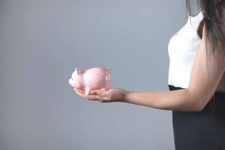 business woman hand piggy bank on grey backgroundの写真素材