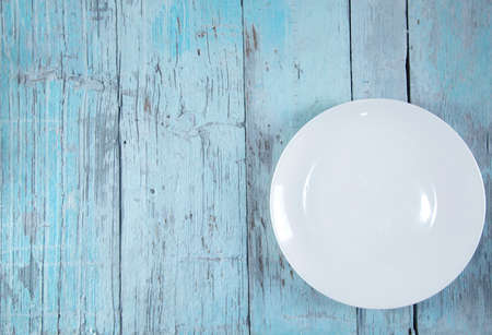 white plate on the blue wooden table backgroundの写真素材