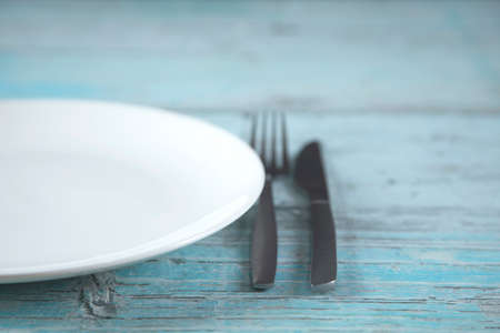 white plate and knife with fork on the tableの写真素材