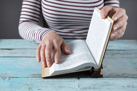 woman hand Holy Bible on the wooden table