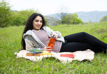 woman hand bottle of water and books in nature