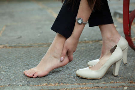 woman ache feet in high shoes in streetの写真素材