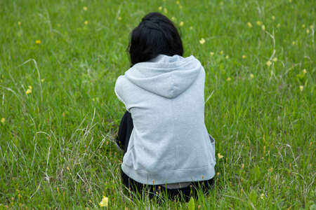 happy woman sitting in green grass in landscapeの写真素材