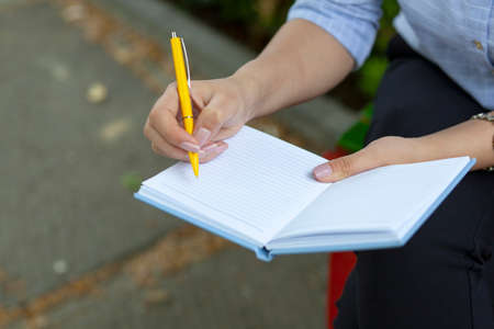 woman hand pen and notepad in park