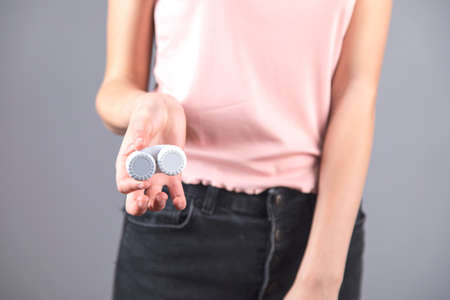 young woman hand holding lenses on gray background