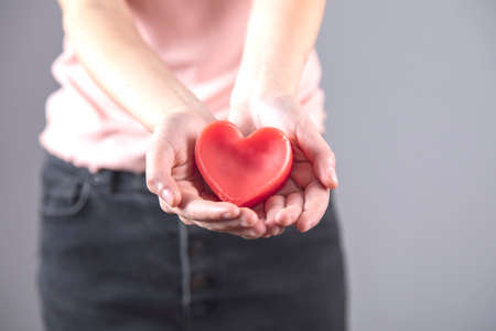 woman hand red heart on the gray background