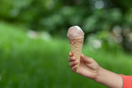 woman hand ice cream on the green grass background