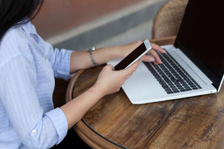 woman hand phone and computer in cafeの写真素材