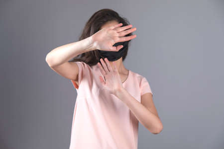 woman face mask and hand stop sign on gray background