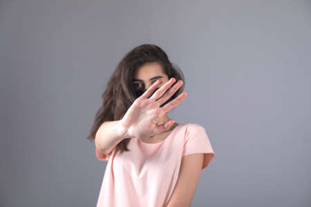 woman face mask and hand stop sign on gray background