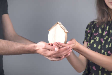 man and woman hand wooden house on gray backgroundの写真素材