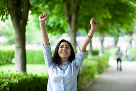 happy woman with raised hands in streetの写真素材