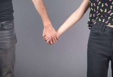 man and woman hand in hand on gray backgroundの写真素材