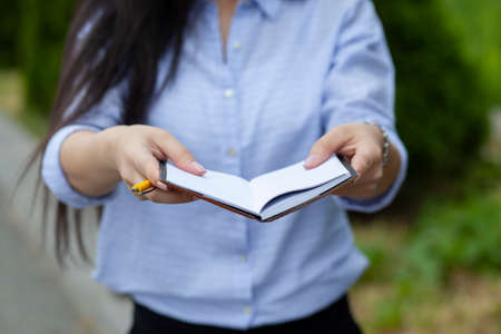 Woman holding pen and notepad in the streetの写真素材