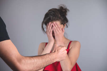 angry man beating woman on gray background