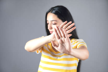 young woman hand stop sign on gray background