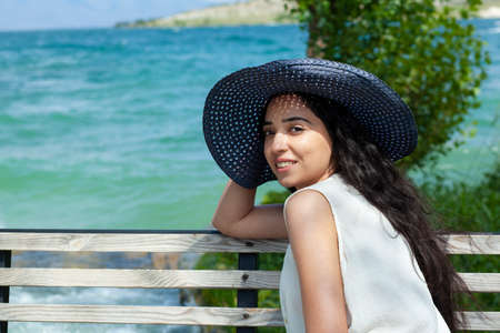woman sitting in bench in sea background