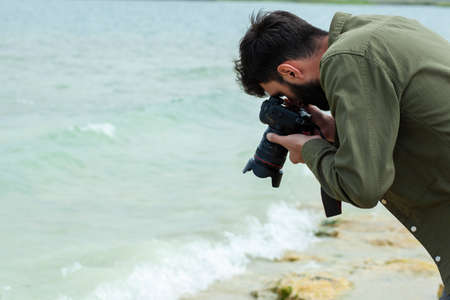 Photographer holding a camera on the beachの写真素材