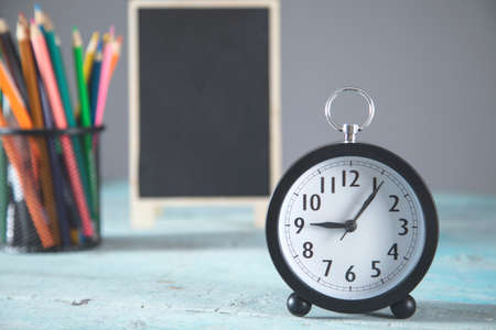 clock and chalkboard with pencils on the table