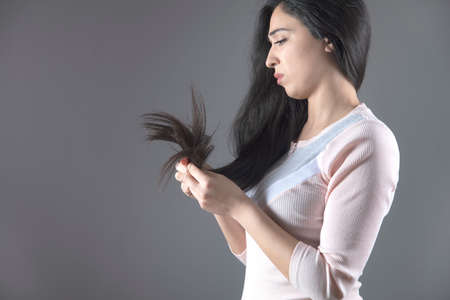 sad woman hand damaged hair on gray backgroundの写真素材