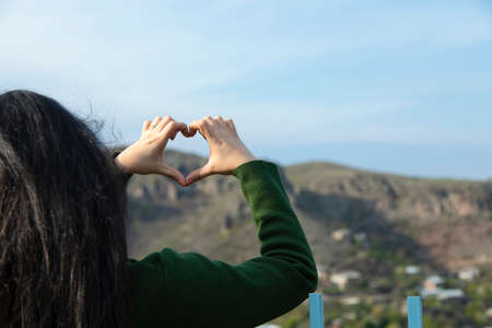 young woman hand heart in the nature