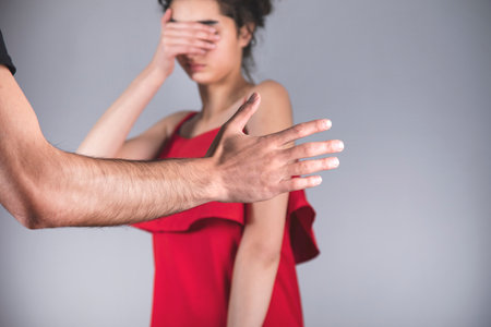 angry man beating woman on gray backgroundの写真素材