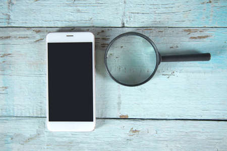 phone and magnifying glass on the tableの写真素材